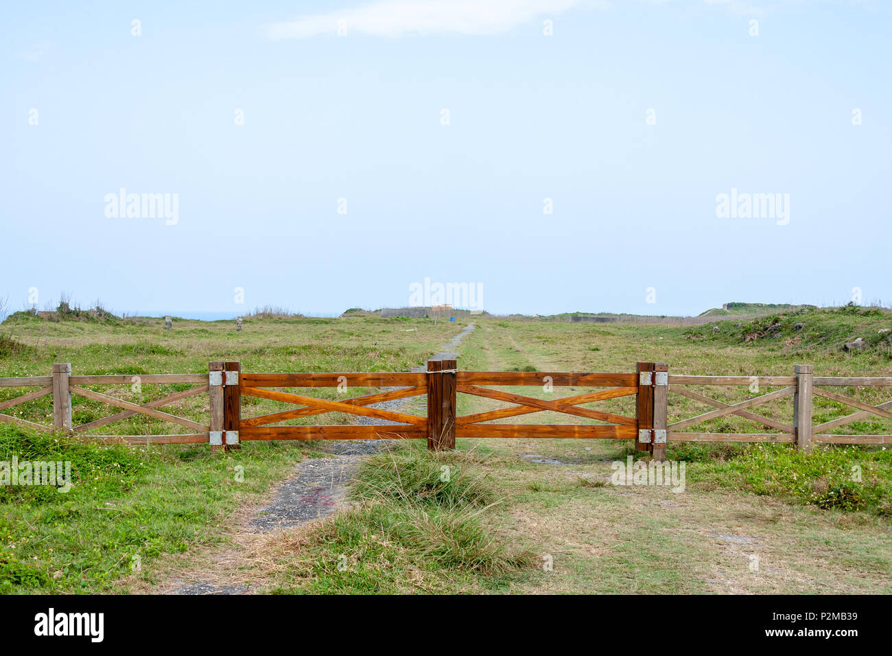Wooden farm gate and fence on open land. Entrance closed, shut, overlooking plain ground, blue sky, countryside, Hualien County, Taiwan Stock Photo