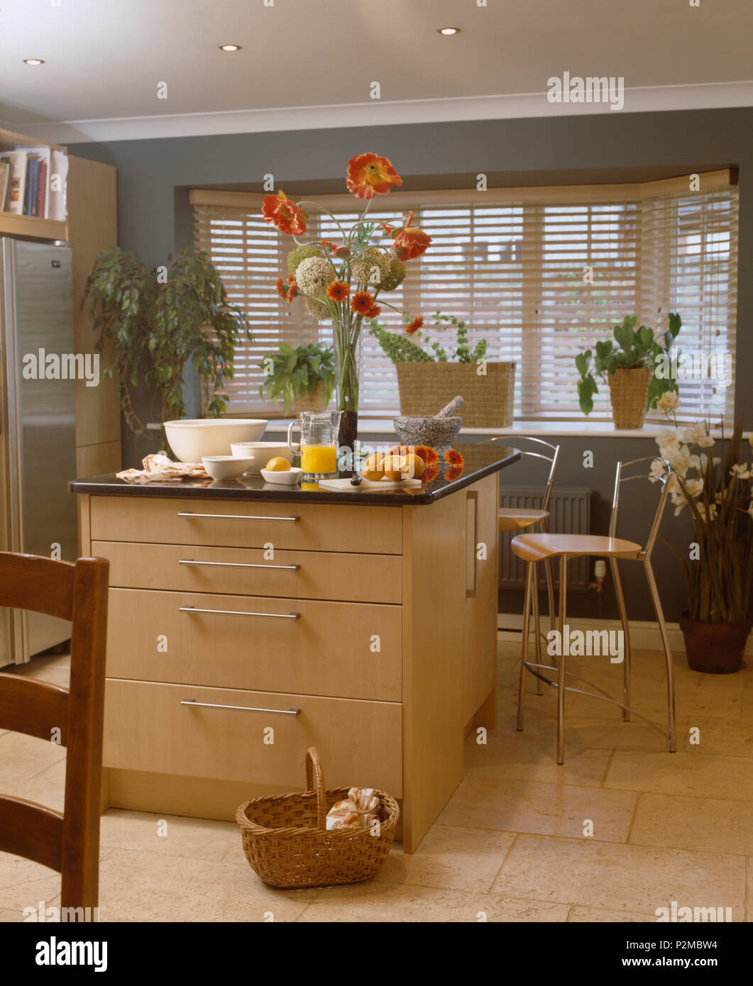 Tall floral display on island unit in modern kitchen with travertine tiled floor Stock Photo