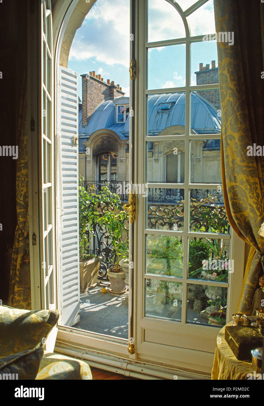 Open French windows onto small balcony of Paris apartment with view of townhouses Stock Photo