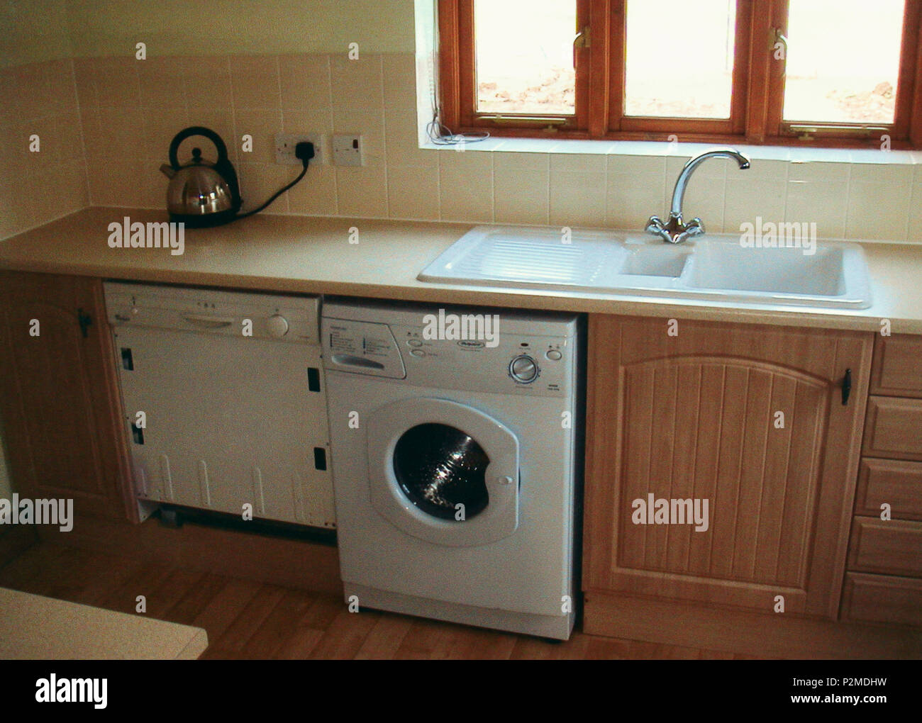 Kitchen with washing machine and dishwasher below double white sink Stock  Photo - Alamy