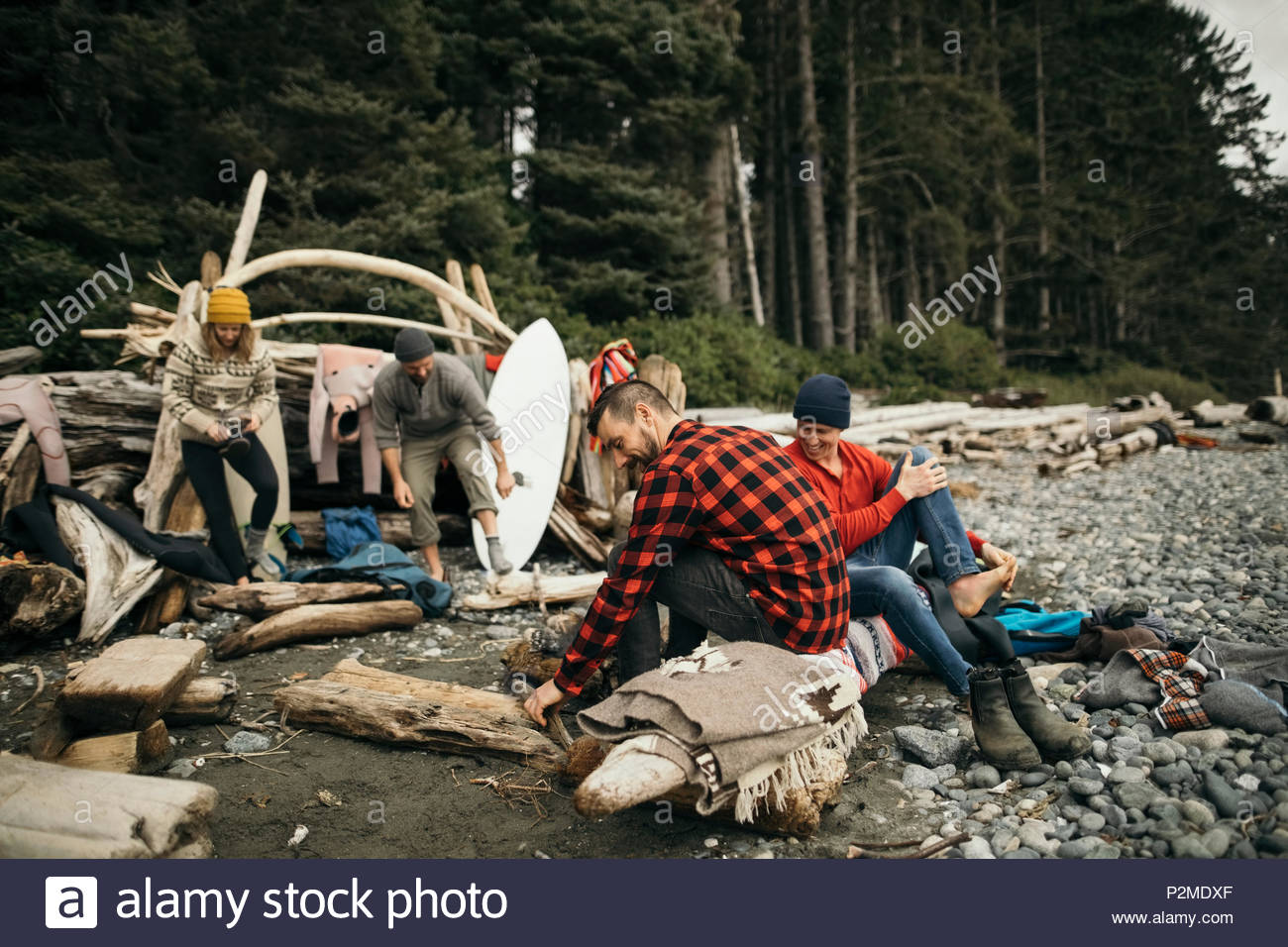 Friends enjoying weekend surfing getaway, relaxing at campsite on rugged beach Stock Photo