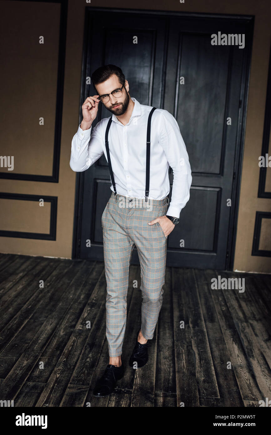 fashionable elegant man posing in white shirt and suspenders in loft  interior Stock Photo - Alamy