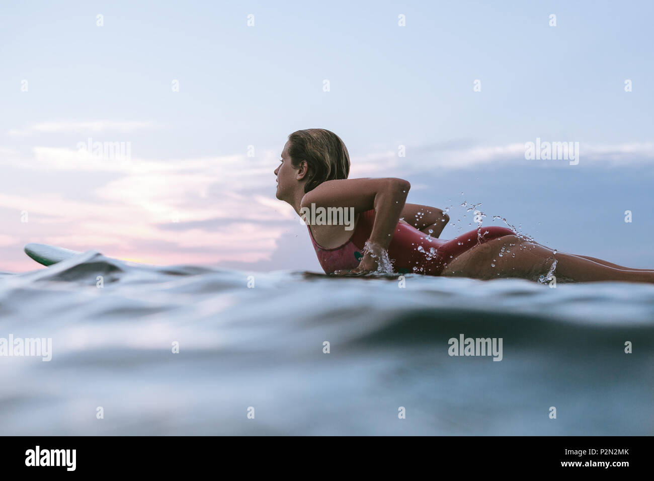 side view of sportswoman in swimming suit with blue surfing board