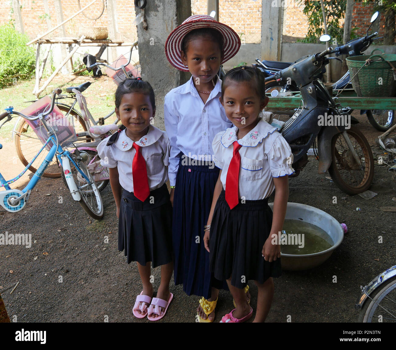 Cambodian schoolgirls, smartly dressed in their school uniform, ready to cycle to school at 07.00 in the morning. Kampong Thom province, Cambodia. Stock Photo