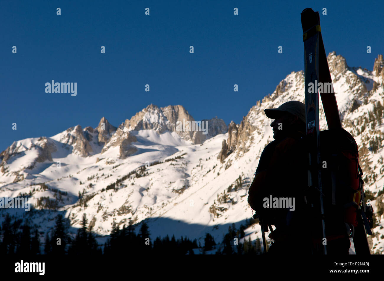 Backcountry skier in silhouette with ski gear and mountains below Matterhorn peak in the High Sierra, California, USA. Stock Photo