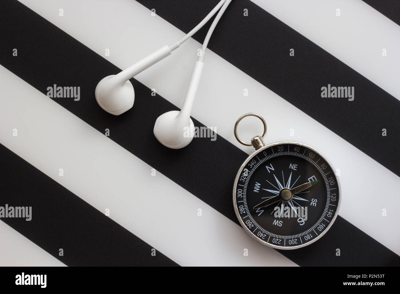 headphones and compass on black and white background, concept travel with music Stock Photo