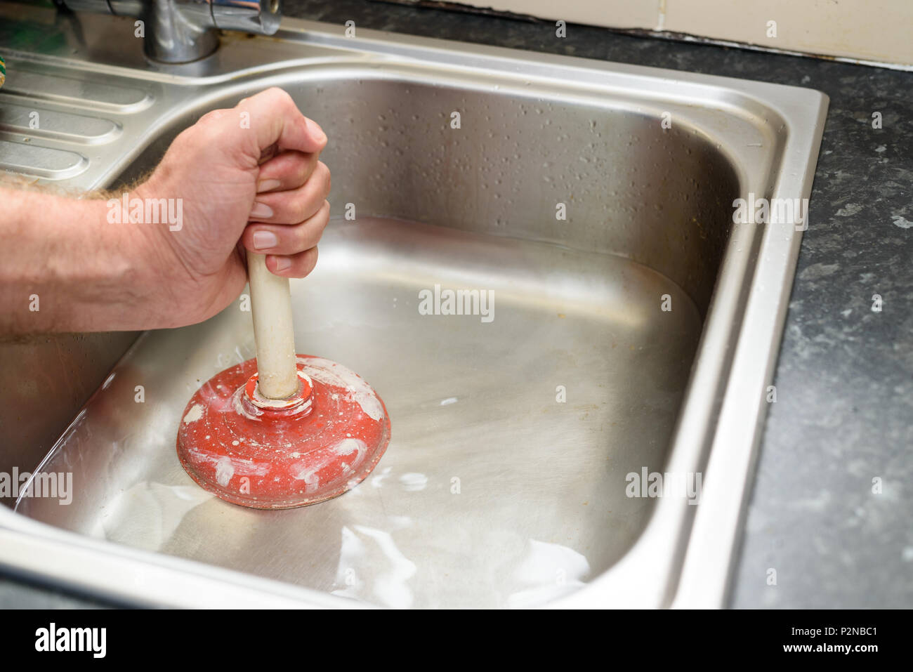 https://c8.alamy.com/comp/P2NBC1/man-holding-a-plunger-with-one-hand-and-water-in-sink-used-to-clean-a-clogged-blocked-kitchen-sink-P2NBC1.jpg