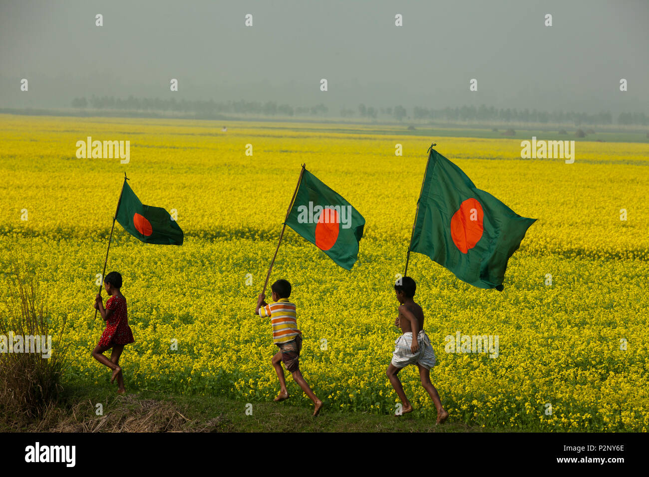 Bangladeshi rural children run with Bangladeshi national flag through a