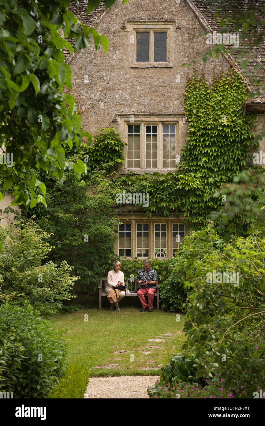 UK, England, Oxfordshire, Kelmscott Manor, William Morris’ home, visitors relaxing on seat in in rear garden Stock Photo