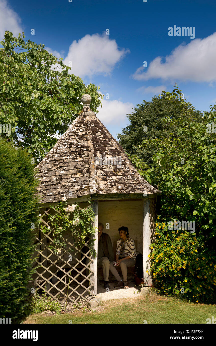 UK, England, Oxfordshire, Kelmscott Manor, William Morris’ home, visitors in shady front garden gazebo with stone tiled roof Stock Photo