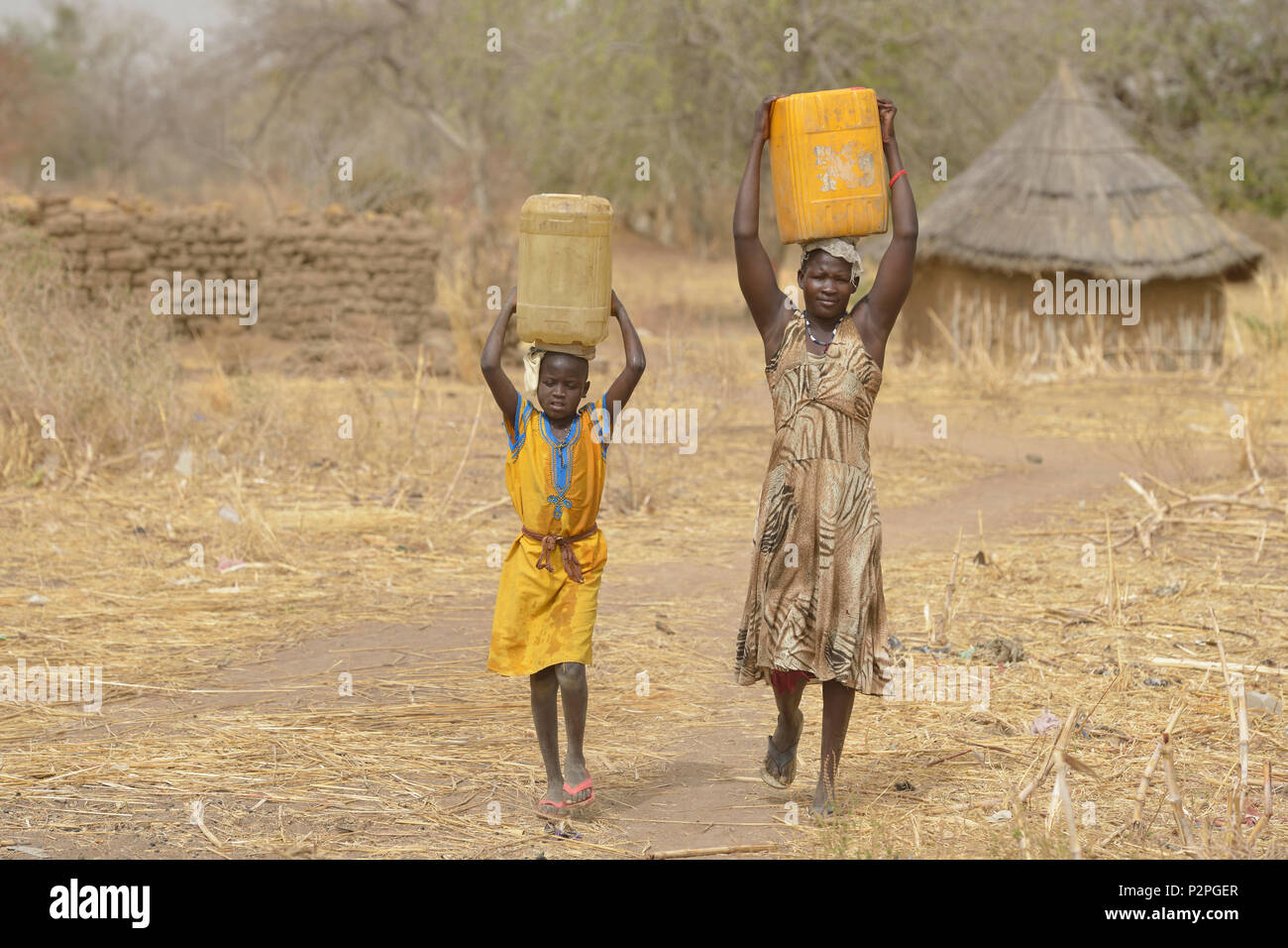 With help from her 8-year old daughter Atap, Atouc Dut carries home water from a well in Malek Miir, a village in South Sudan's Lol State. Stock Photo