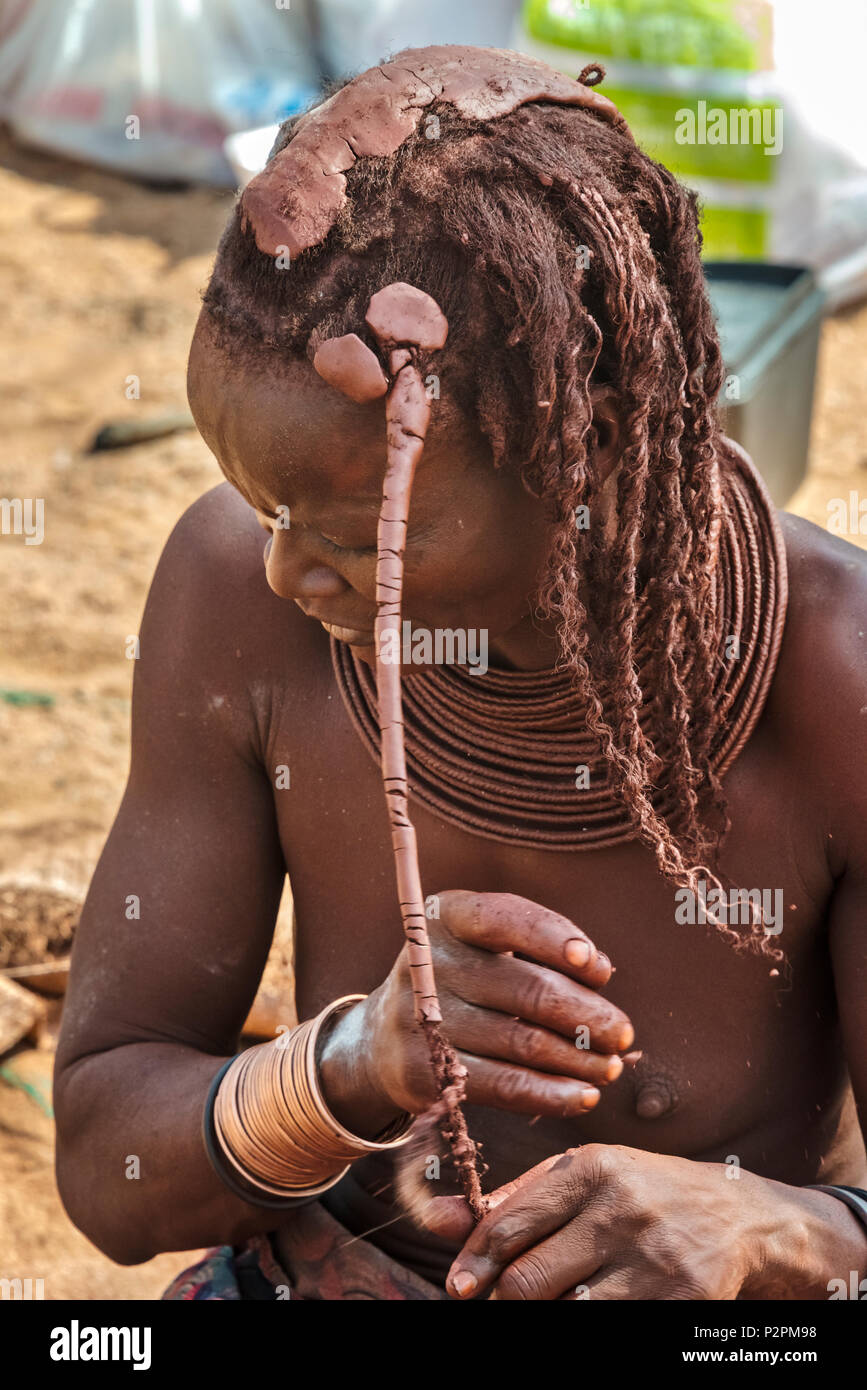 Himba girl using red clay to braid hair, Damaraland, Kuene Region, Namibia Stock Photo