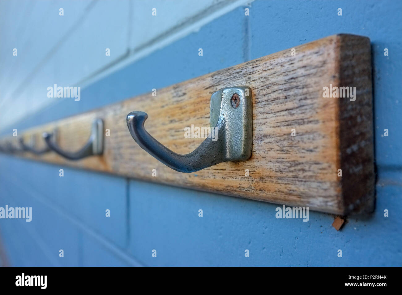 Metal hooks against a blue bricks wall. Hooks rack. Stock Photo