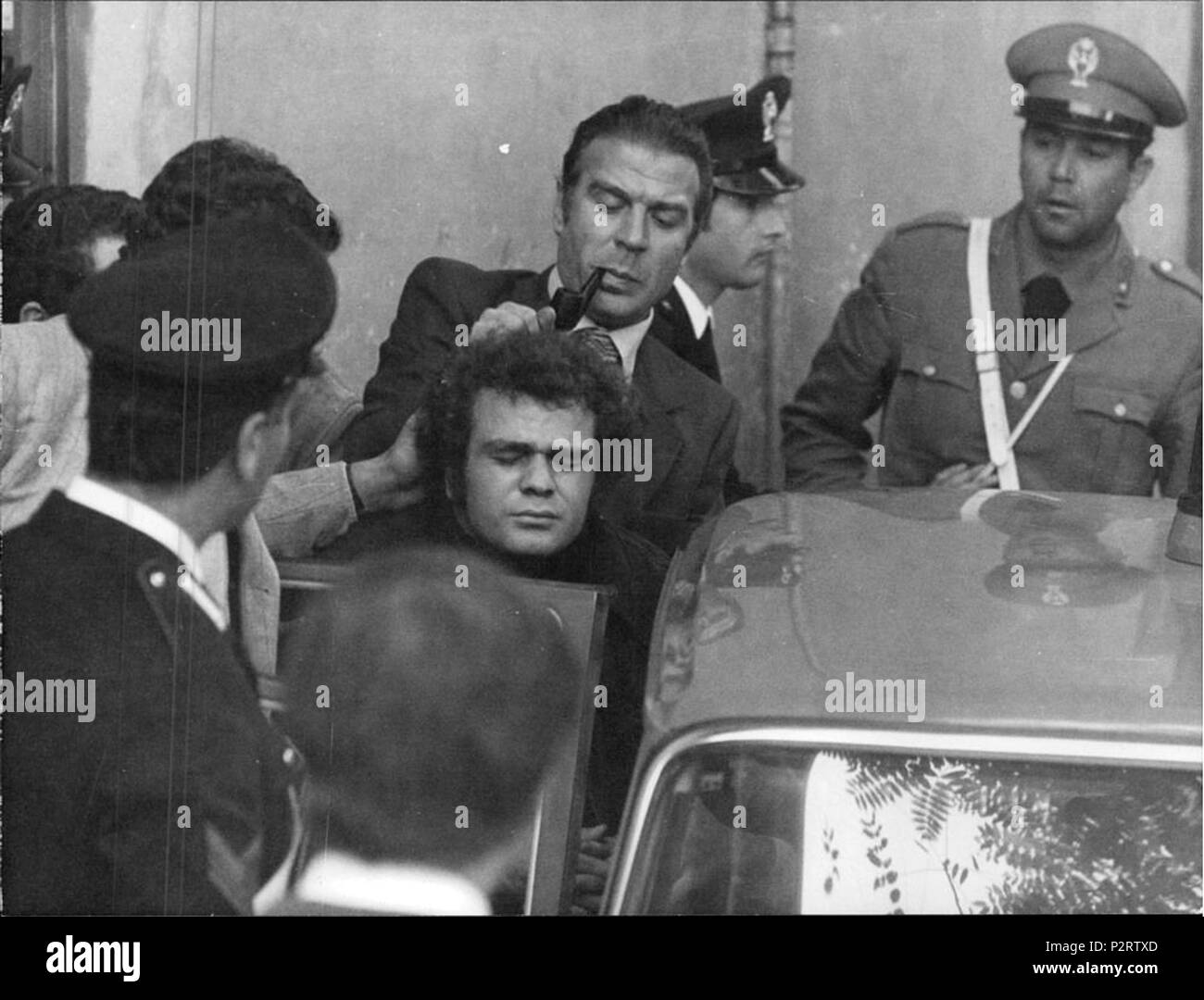 . English: An angry 'Brigadiere' (rank equivalent with sergeant) of Milan's criminal police holds the hair of 23 year old gangster Ruggero Russo. At about 10 o'clock this morning, four gangsers inside a speedy car stopped in front of the bank agency nr. 13 of the 'Banco di Roma'. Three entered the bank , drew out arms and got away with about seventeen million of Italian Lire. A few minutes later, the police started pursue. Two hours later, two of the gangsters were cautght. Two others 'went over the hill' but it appears as if they too will soon finish inside of the 'Black Mary'. 9 October 1972 Stock Photo