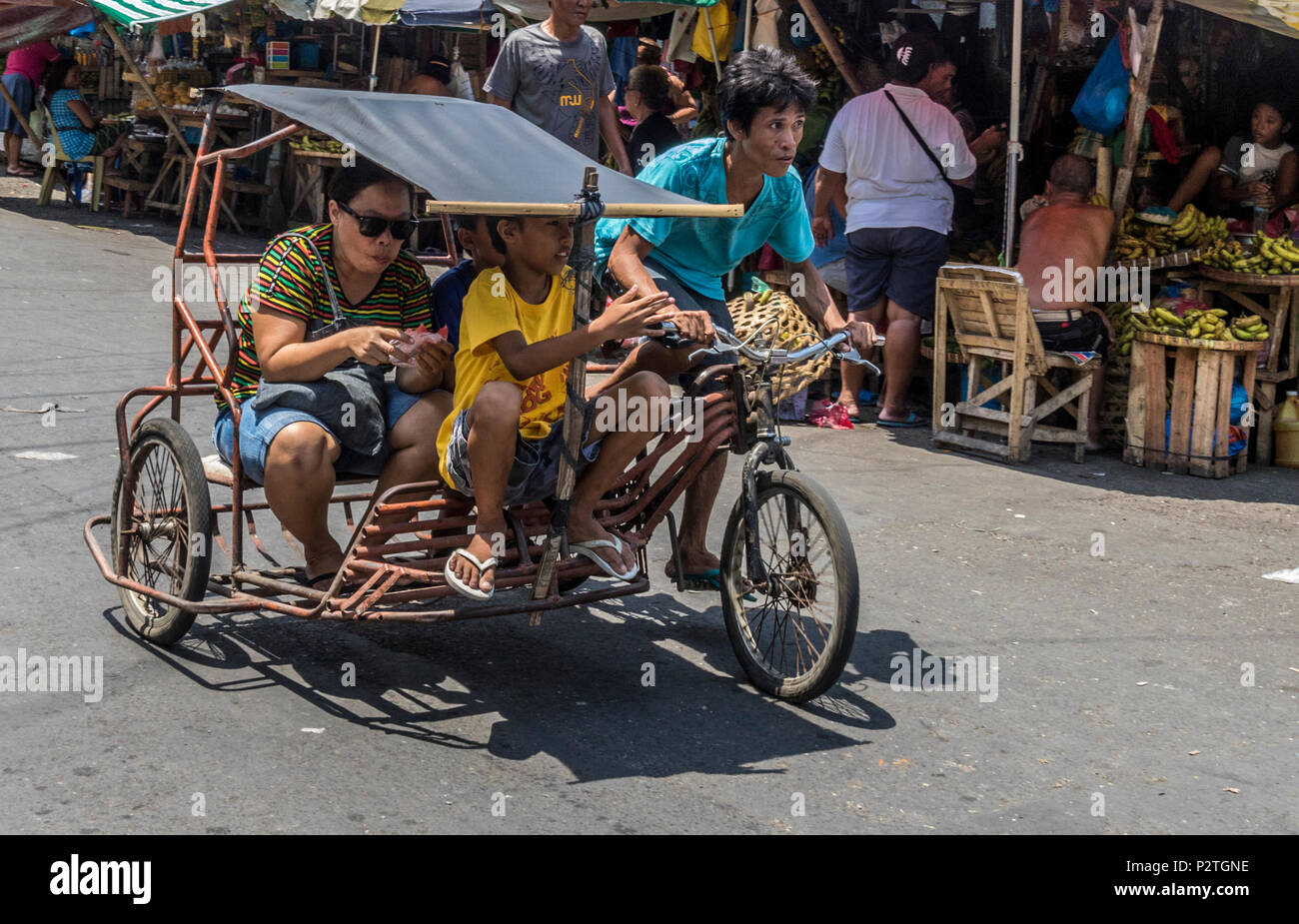 Goods and people being over around carbon public market on tricycles in