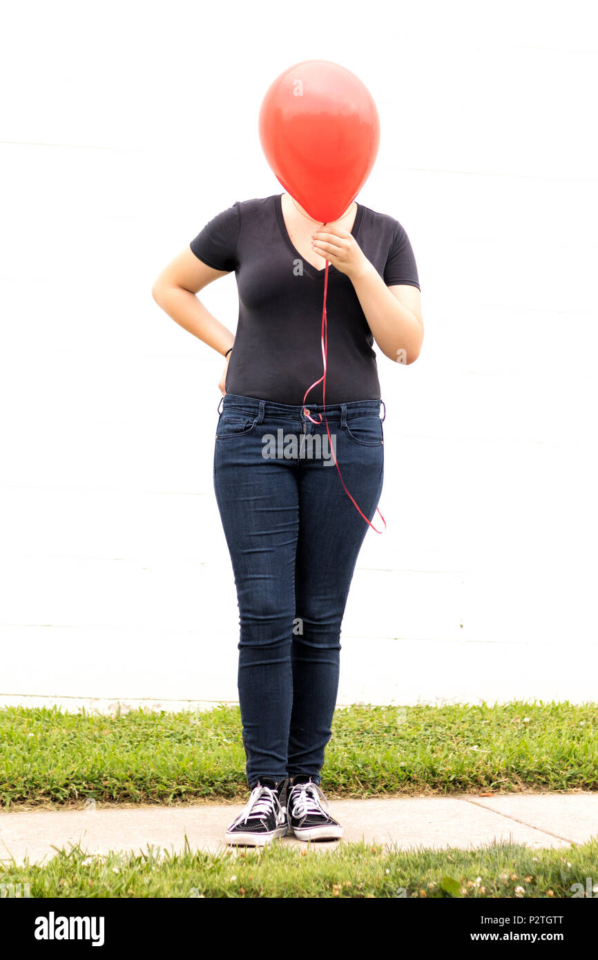 girl hiding behind red balloon Stock Photo