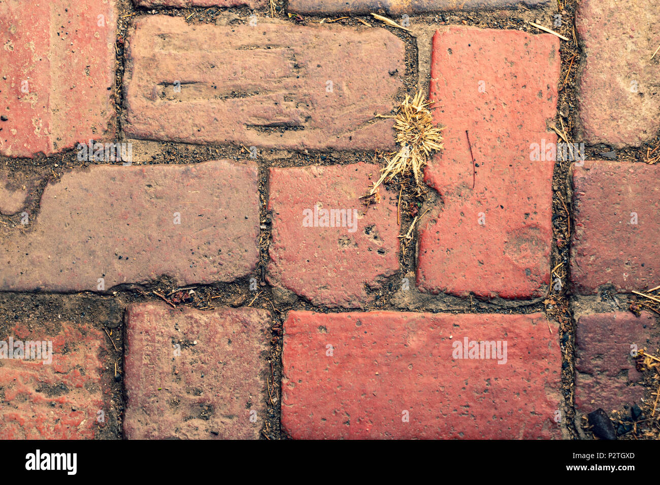 a red brick pathway or road, the bricks are well worn Stock Photo