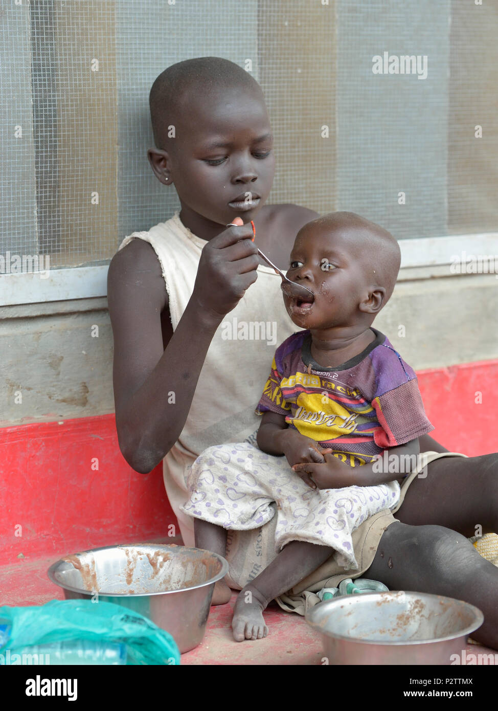 A girl feeds her sibling in a supplemental feeding program for malnourished children and mothers run by the Loreto School in Rumbek, South Sudan Stock Photo