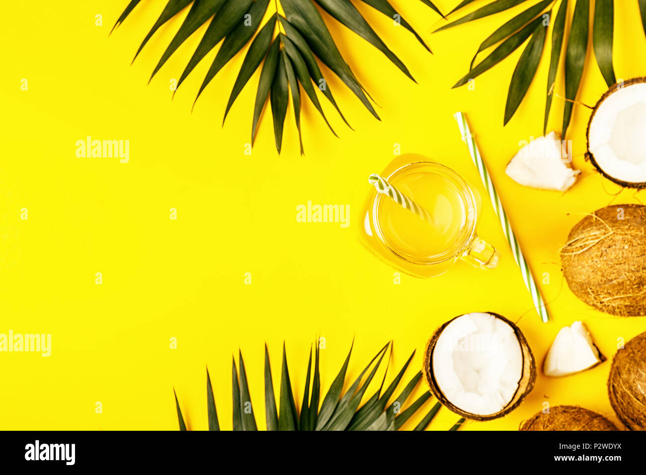 Coconut water and coconuts on a background with tropical leaves Stock