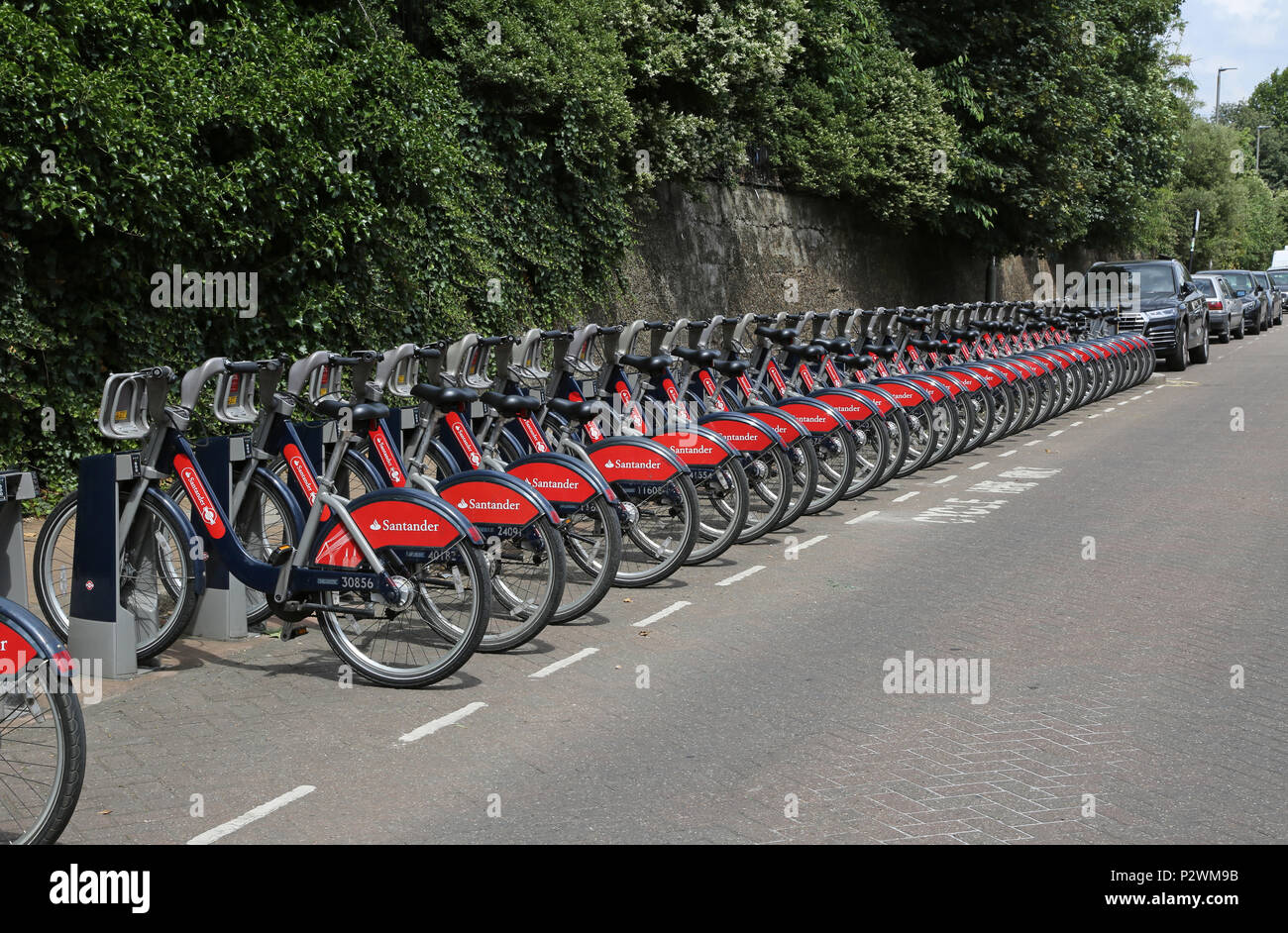 A long line of Santander-branded hire bikes in a docking station near Wandsworth Town railway station in southwest London, UK Stock Photo