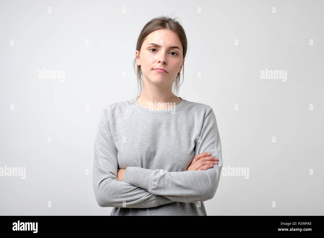 Disappointment, confusion, bad mood. Frustrated young woman with crossed hands stands isolated on white. Stock Photo