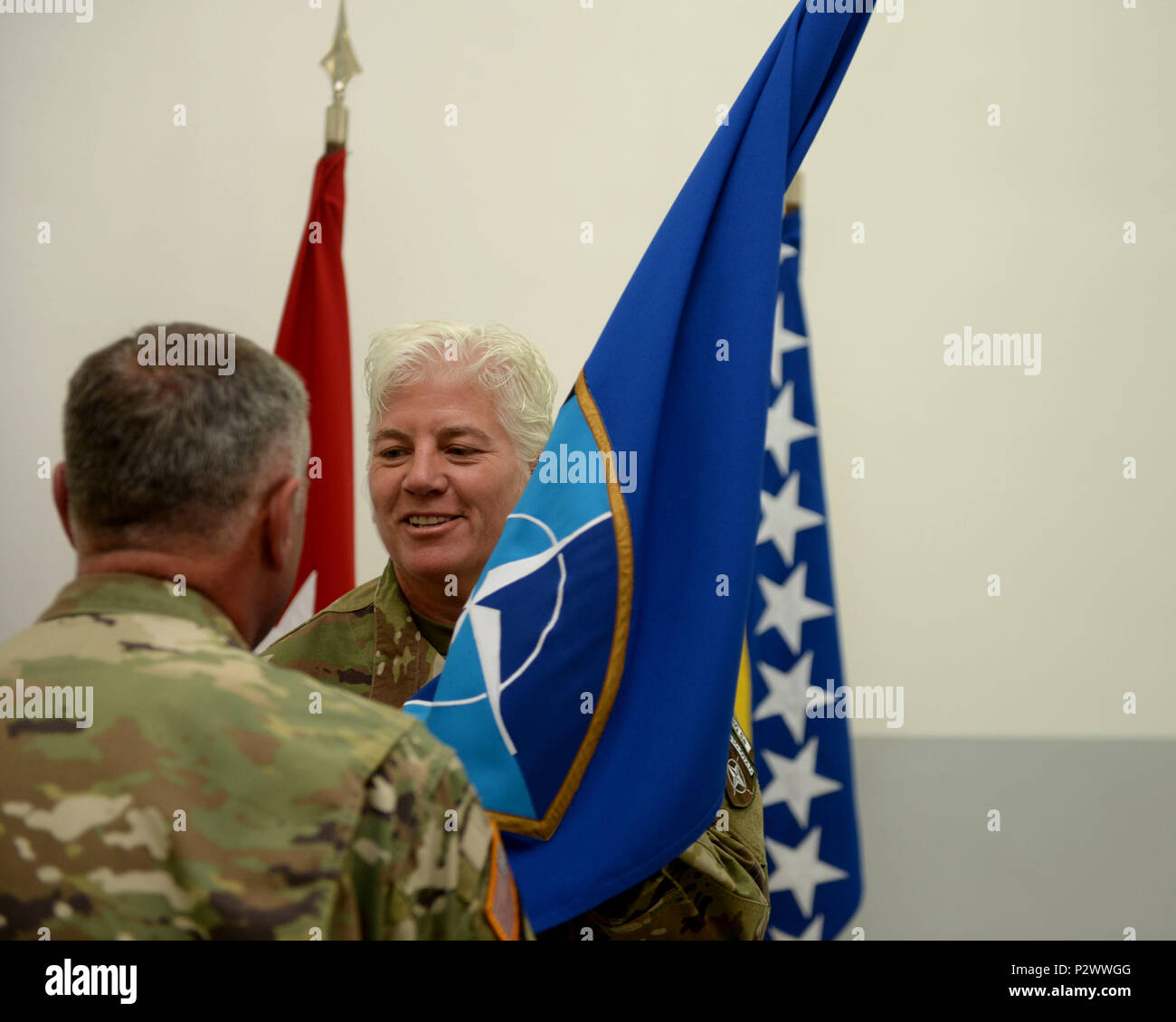 Command Sgt. Maj. Harley J. Schwind Jr. passes the colors to Brig. Gen. Giselle Wilz, NATO Headquarters Sarajevo commander, indicating the return of the responsibilities that where entrusted upon him during a ceremony on Camp Butmir, Bosnia and Herzegovina (BiH), Aug. 2, 2016. Stock Photo
