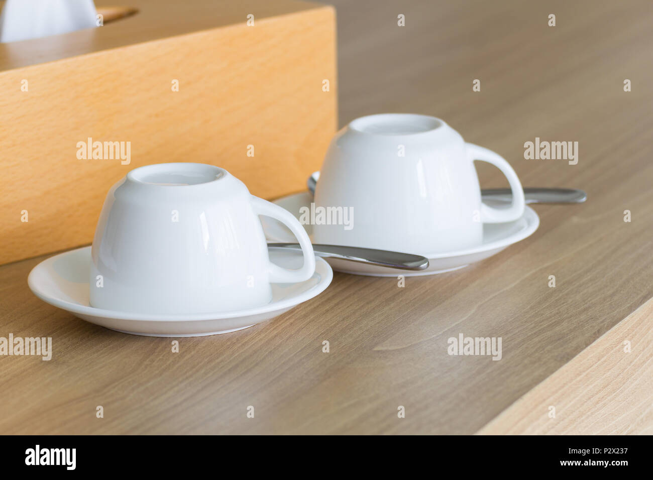New white cups coffee set upside-down on wooden table. Stock Photo