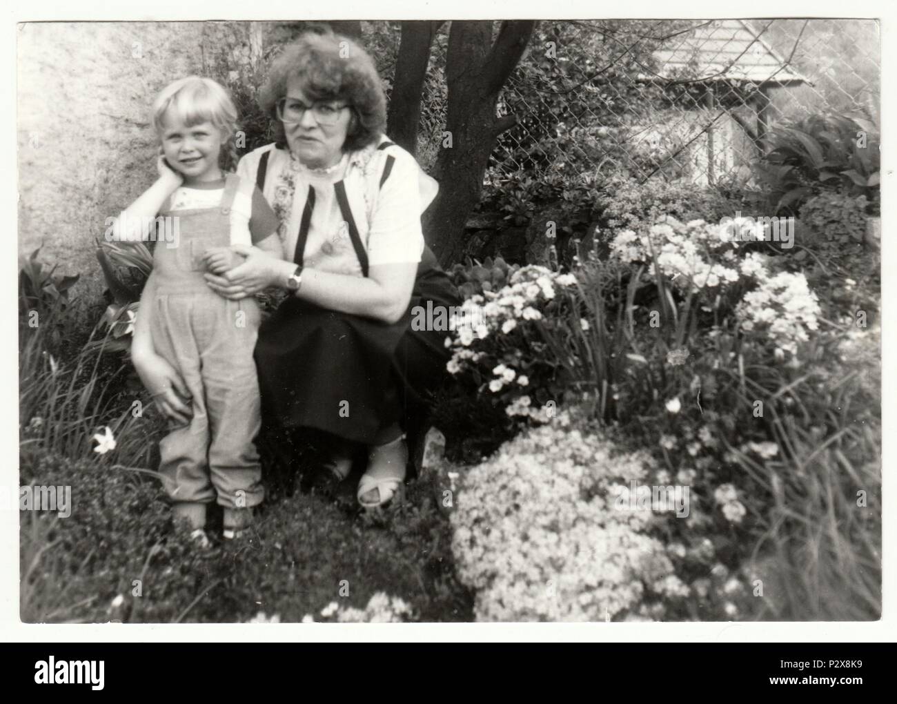 THE CZECHOSLOVAK SOCIALIST REPUBLIC - CIRCA 1980s: Vintage photo shows woman with a small girl in the garden. Holidays in the summertime. Retro black & white  photography Stock Photo