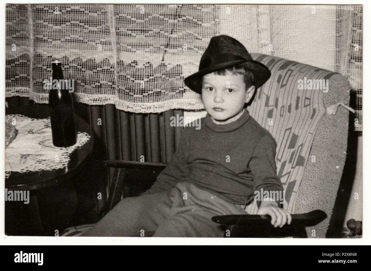 THE CZECHOSLOVAK SOCIALIST REPUBLIC - FEBRUARY 1, 1967: Vintage photo shows a small boy with a bottle of beer. Funny and cute photo of boy. Retro black & white  photography. Stock Photo
