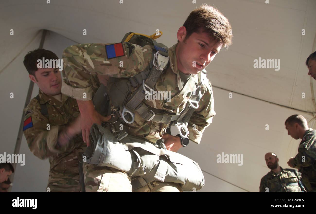 Two British Paratroopers helps each other rig their MC-6 Parachute during Leapfest 2016 at the University of Rhode Island, West Kingston, R.I., August 6, 2016. Leapfest is the largest, longest standing, international static line parachute training event and competition hosted by the 56th Troop Command, Rhode Island Army National Guard to promote high level technical training and esprit de corps within the International Airborne community. (U.S. Army photo by Sgt. Austin Berner/Released) Stock Photo