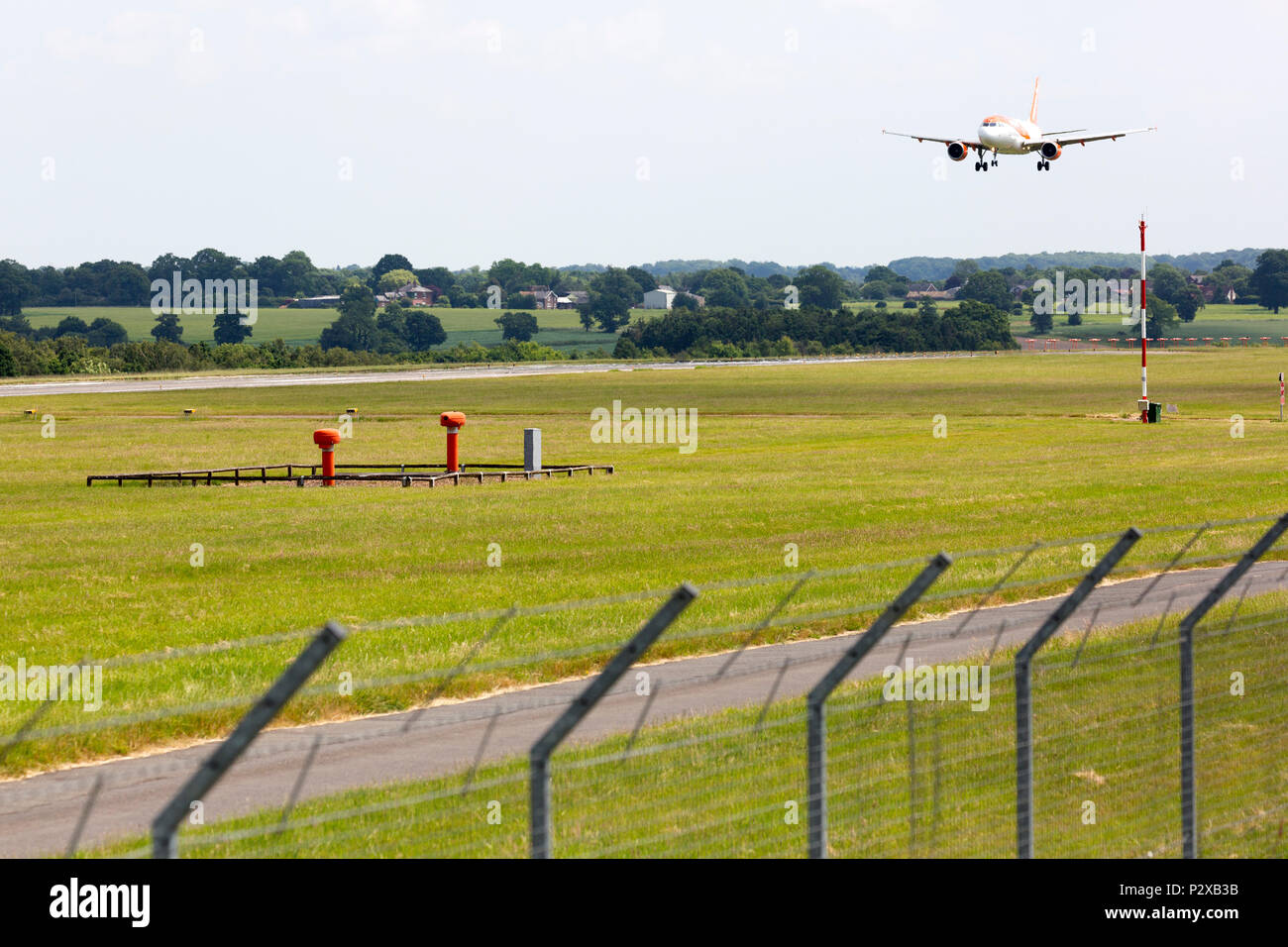 A commercial jet airliner landing at a large city airport, with barbed wires security fence, and airport landing instruments. Stock Photo