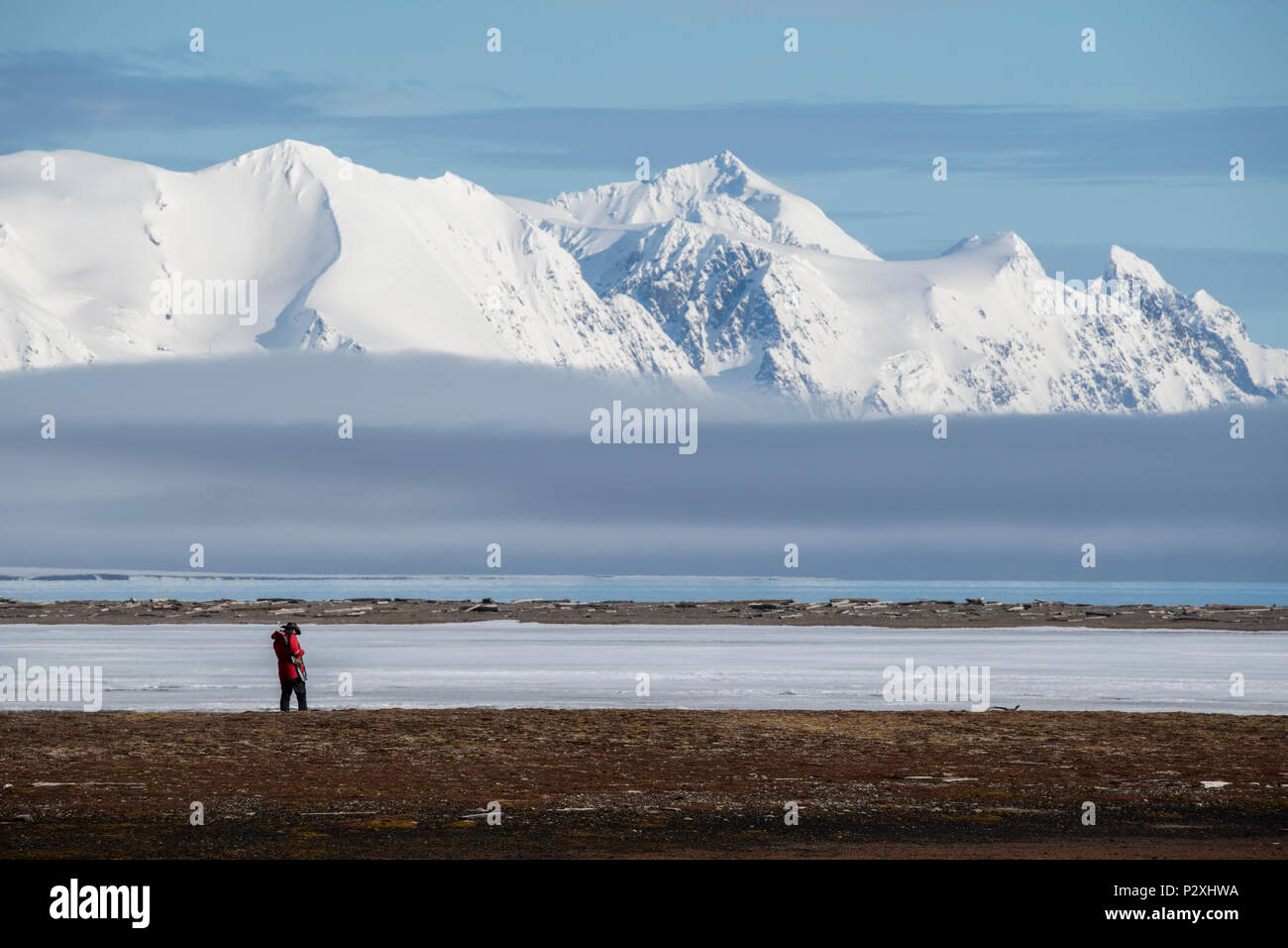 Norway, Svalbard, Spitsbergen, Isfjord, Poolepynten. Scenic view of fjord, hiker with gun (for polar bear protection) Stock Photo