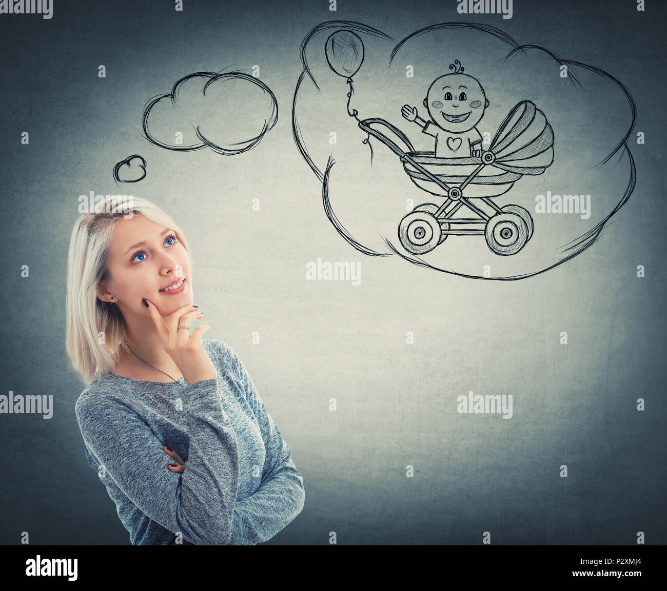 Portrait of thoughtful woman looking up and imagining a baby in his stroller. Dreaming of a child with a positive face expression, isolated on grey wa Stock Photo