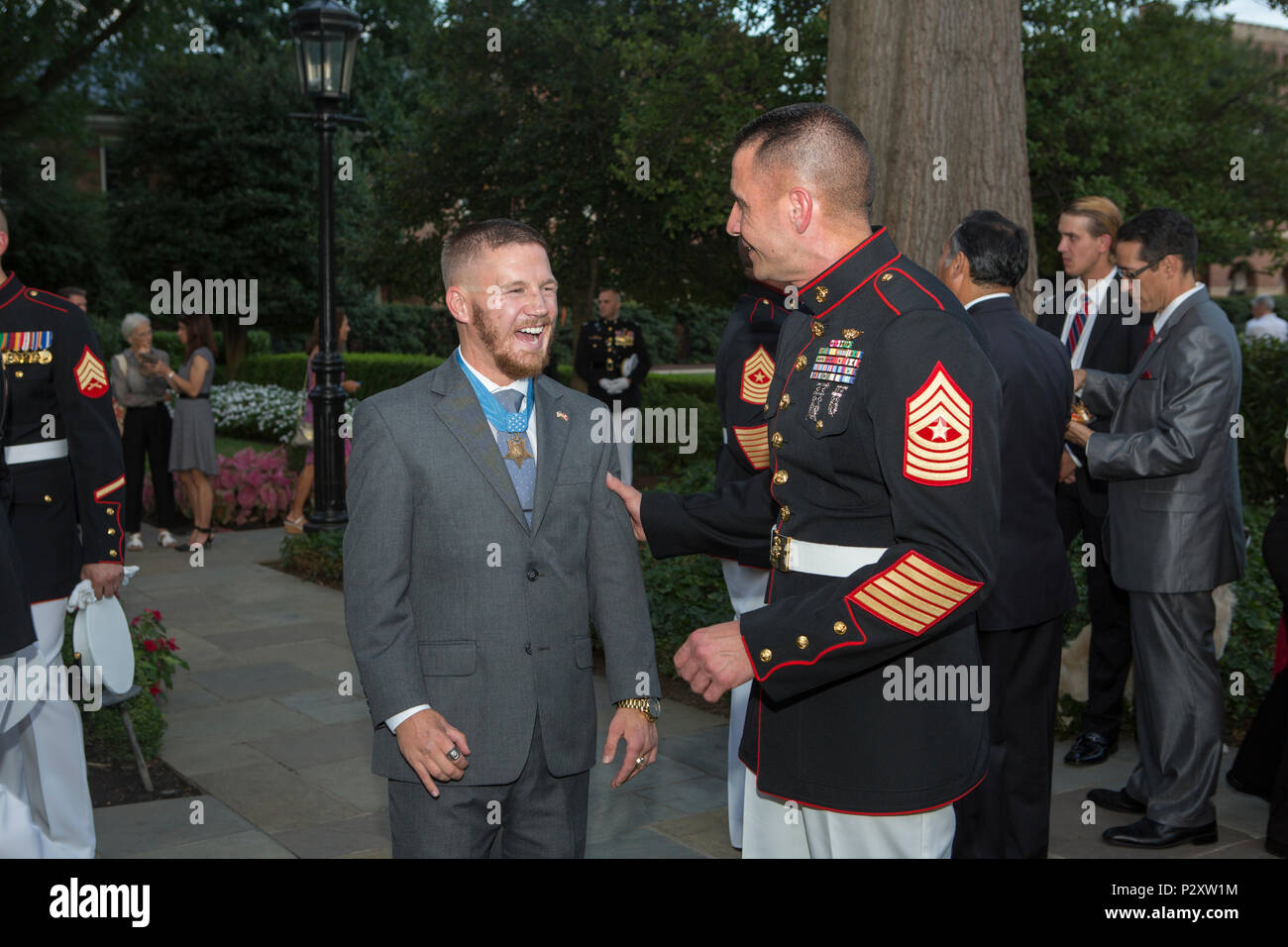 Retired U.S. Marine Corps Cpl. William Kyle Carpenter, Medal of Honor recipient, speaks to Sgt. Maj. Anthony Cruz, Sgt. Maj., Marine Corps Installations Command, during the evening parade reception in the Marine Family Garden, Marine Barracks Washington, Washington, D.C., Aug. 5, 2016. Evening parades are held as a means of honoring senior officials, distinguished citizens and supporters of the Marine Corps. (U.S. Marine Corps photo by Cpl. Christian J. Varney) Stock Photo