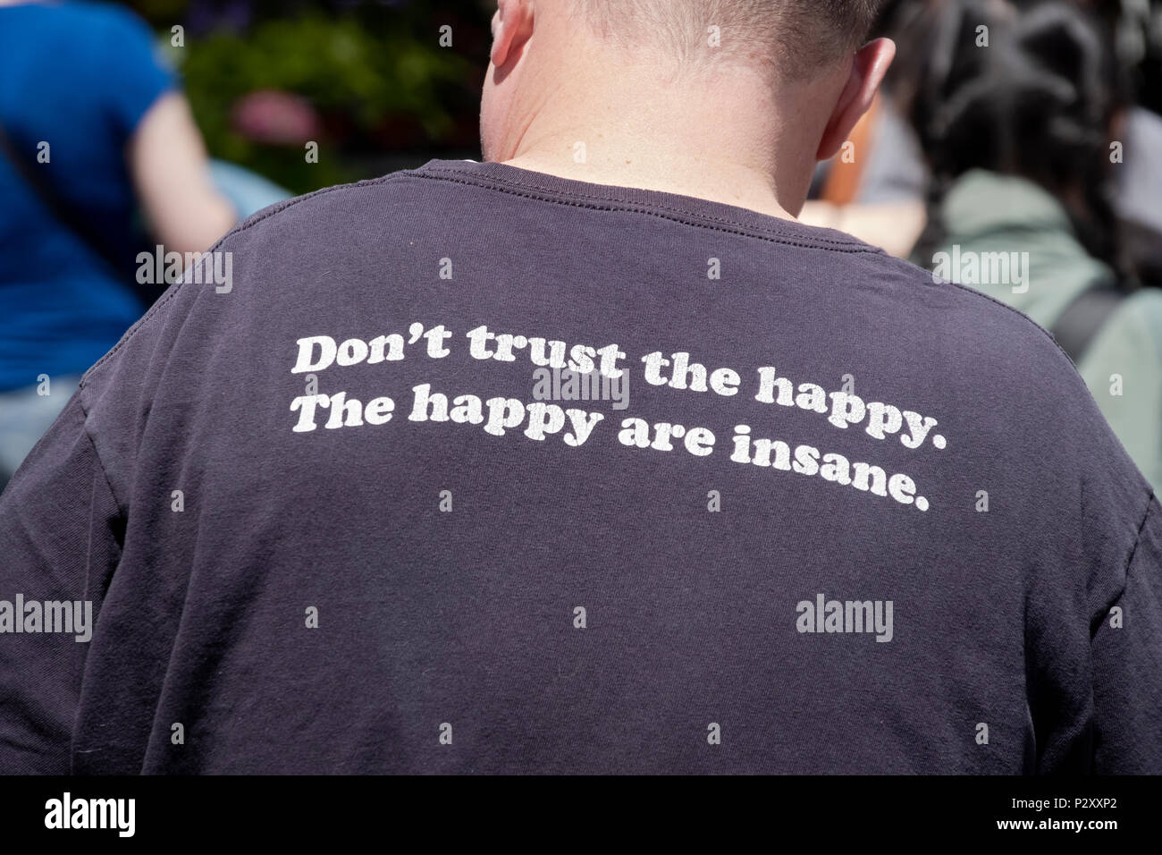 A funny message on the back of a tee shirt saying that happy people are insane & not trustworthy. In lower Manhattan, New York City. Stock Photo