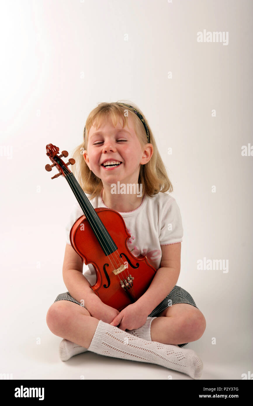 happy little girl holding a violin - generic Stock Photo