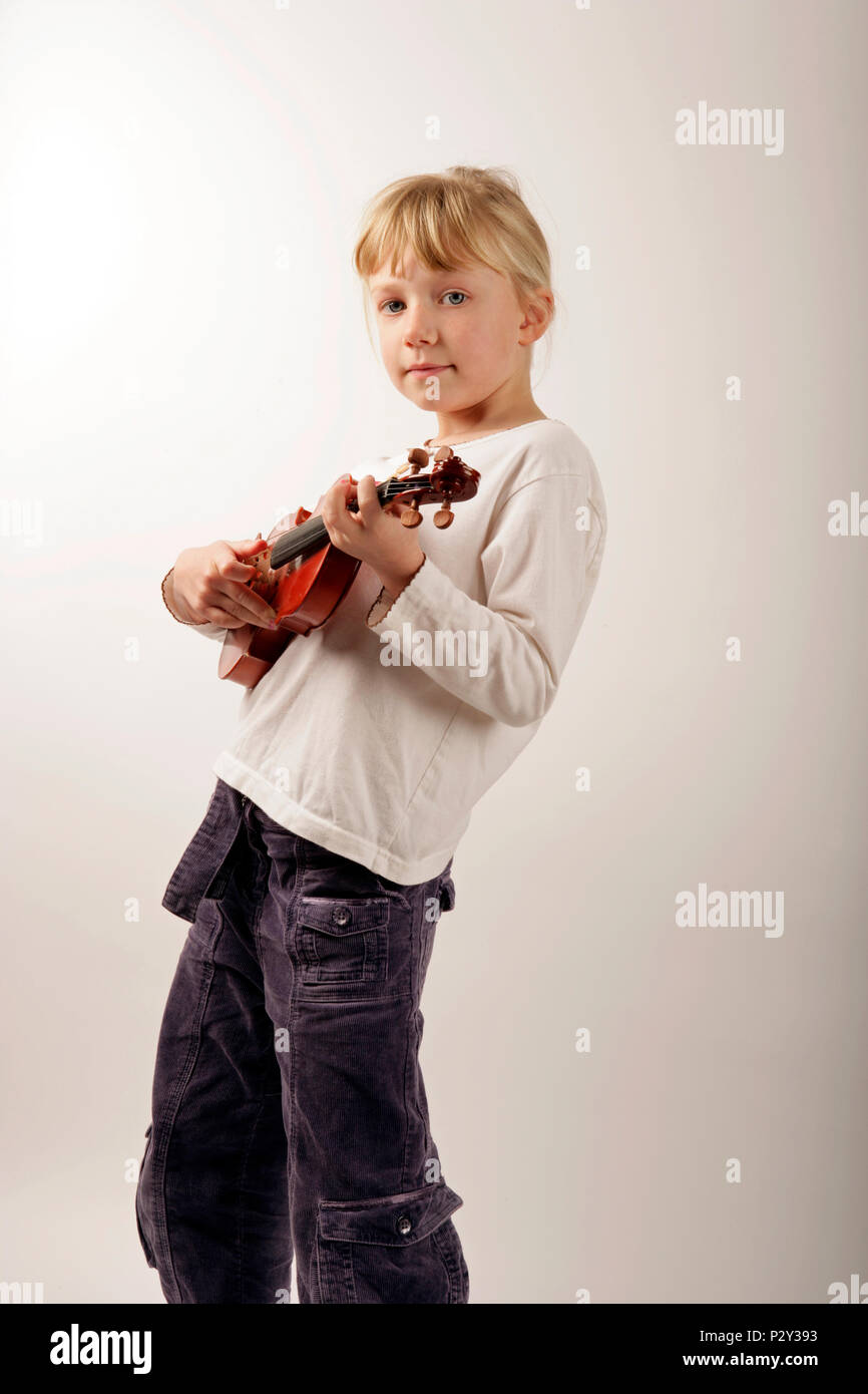young girl plucking a guitar whilst holding the violin like a guitar Stock Photo