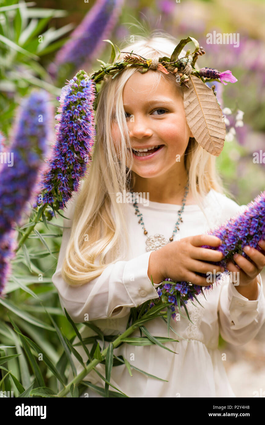 Laughing blond girl in rural chic forest fashion clothing in a forest setting with flowers. Stock Photo