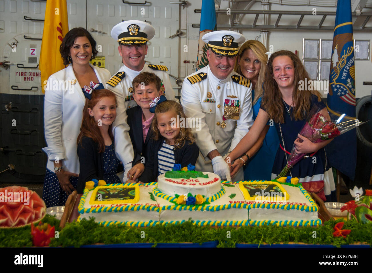 160804-N-EW322-228 SAN DIEGO (Aug. 4, 2016) – Capt. Mark Melson, the incoming Commanding Officer of the amphibious assault ship USS Makin Island (LHD 8), left, Capt. Jon P. Rodgers, the outgoing Commanding Officer, right, and their families cut a cake during a change of command ceremony in the ship’s hangar bay. Makin Island is homeported in San Diego. (U.S. Navy photo by Mass Communication Specialist Seaman Clark D. Lane/Released) Stock Photo