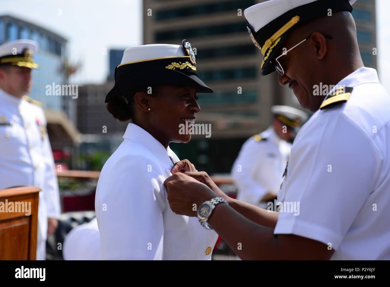 160806-N-DD899-209 BALTIMORE, Md. (Aug. 8, 2016) Cmdr. Tasya Lacy, left, commanding officer of Navy Operational Support Center (NOSC) Batimore, is pinned by her husband, Cmdr. Herb Lacy, right, during a change of command ceremony aboard USS Constellation in Baltimore Inner Harbor. Lacy relieved Cmdr. John B. Downes as the NOSC Baltimore commanding officer. (U.S. Navy photo by Mass Communication Specialist 1st Class Sharay Bennett/Released) Stock Photo