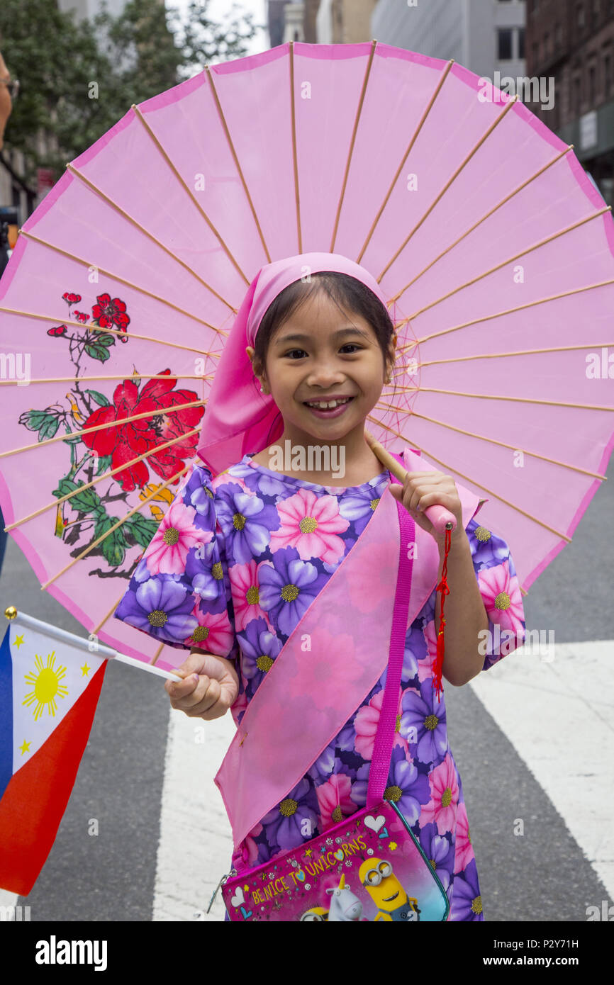 Happy child in a flower dress, flag in hand, marches in the Philippine