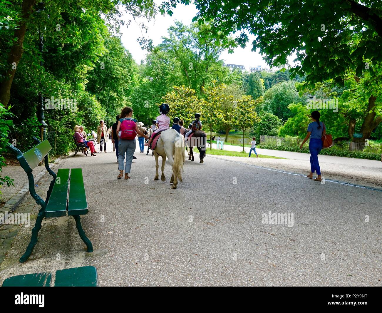 Children riding ponies on a warm Saturday afternoon at Parc Buttes Chaumont in northeastern Paris, France Stock Photo
