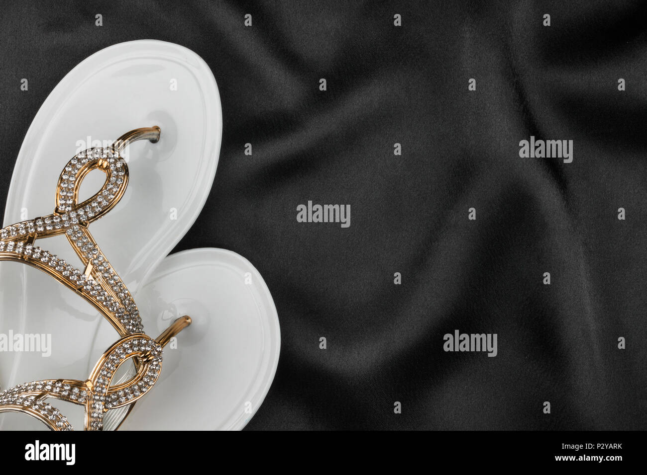 White Flip Flops Decorated With Rhinestones Lies On Black Cloth