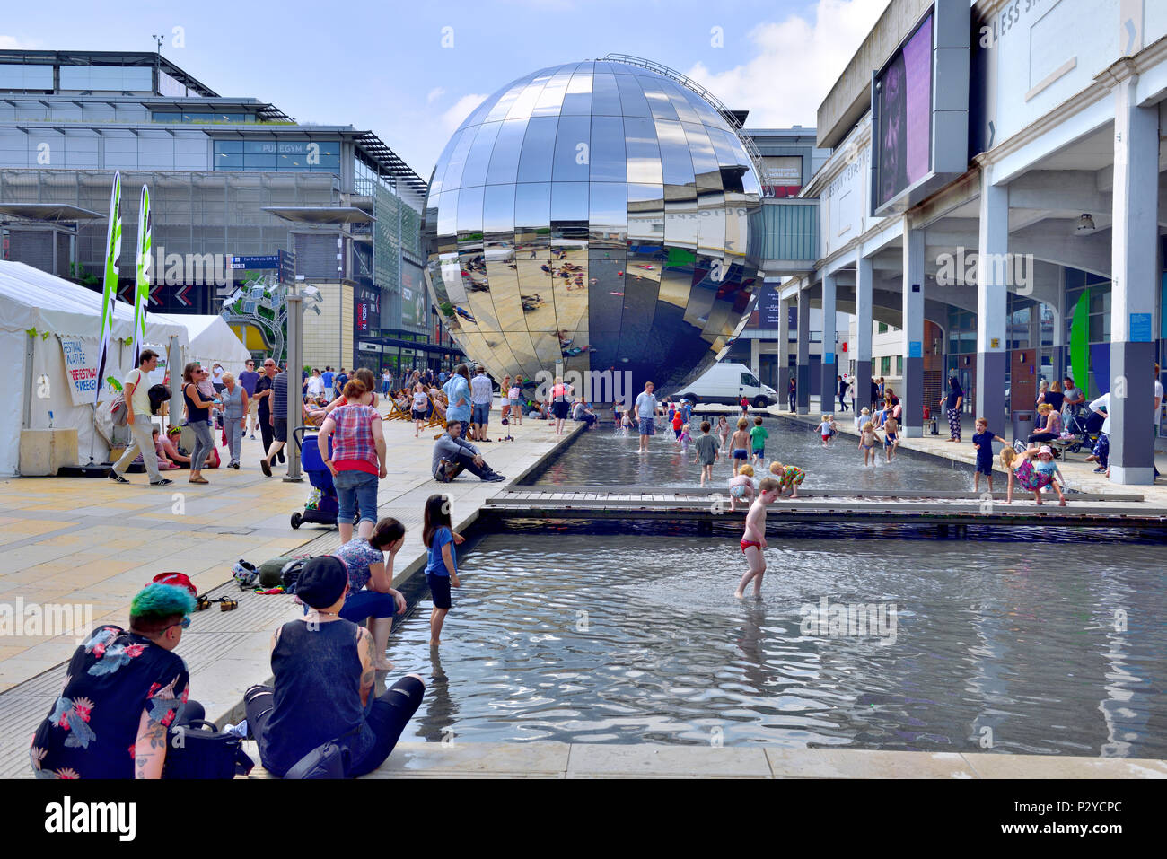 Bristol Millennium Square with shallow pools with kids playing and the mirrored Planetarium, festival tents, UK Stock Photo