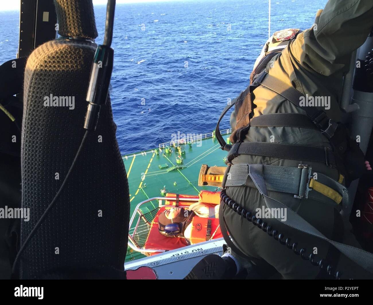 An MH-65 Dolphin helicopter crew from Coast Guard Air Station Barbers Point hoists a 45-year-old man from an oil tanker 14 miles south of Oahu, Aug. 10, 2016. Personnel aboard the Bahamian-flagged oil tanker Andromeda Voyager reported a crewmember with heart attack symptoms to watchstanders at the Joint Rescue Coordination Center in Honolulu. (U.S. Coast Guard photo by Lt. Ron Green/Released) Stock Photo