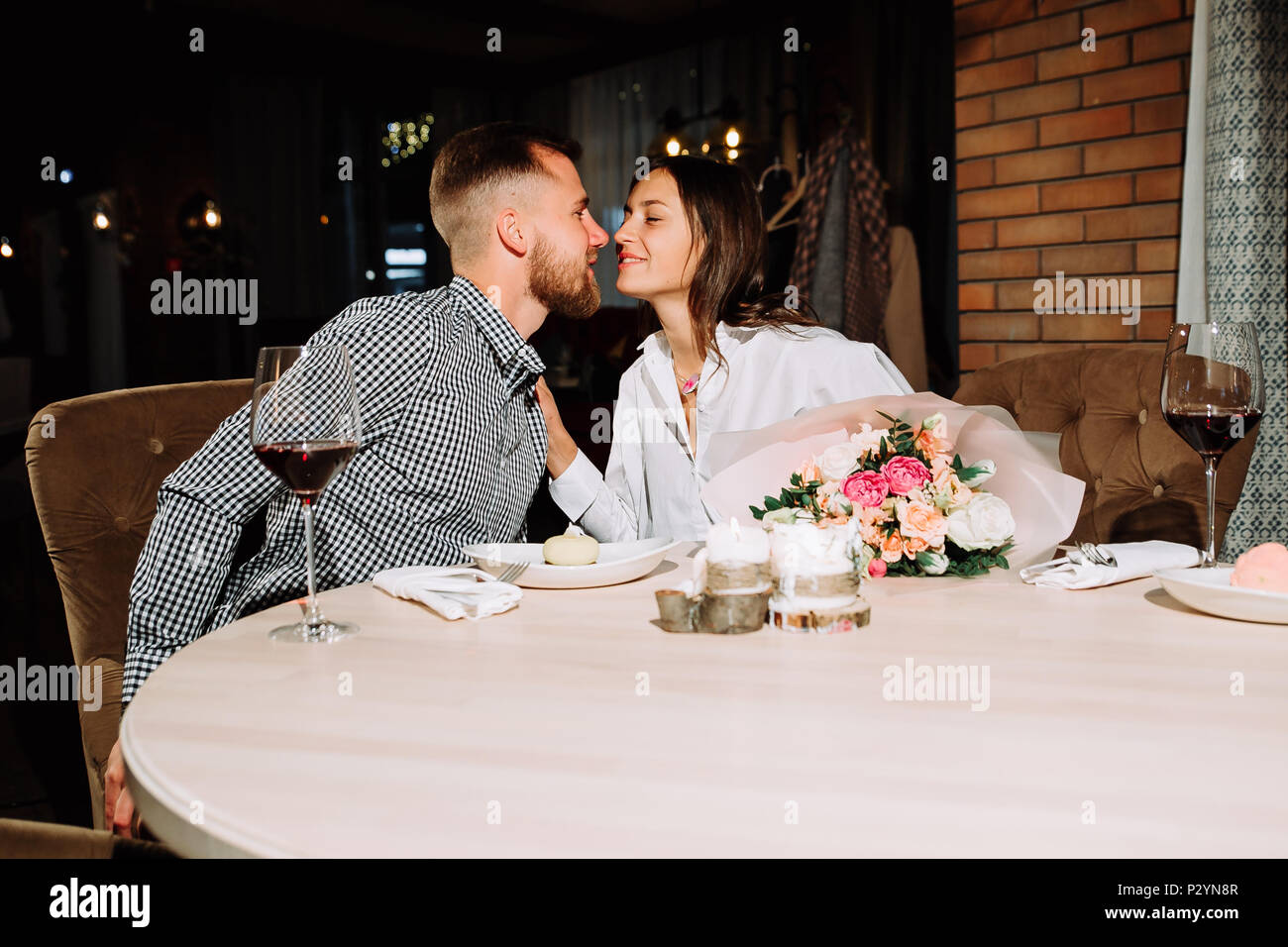 enamored couple sitting in a chair, hug each other and drinking vine in a cafe or restaurant. Stock Photo