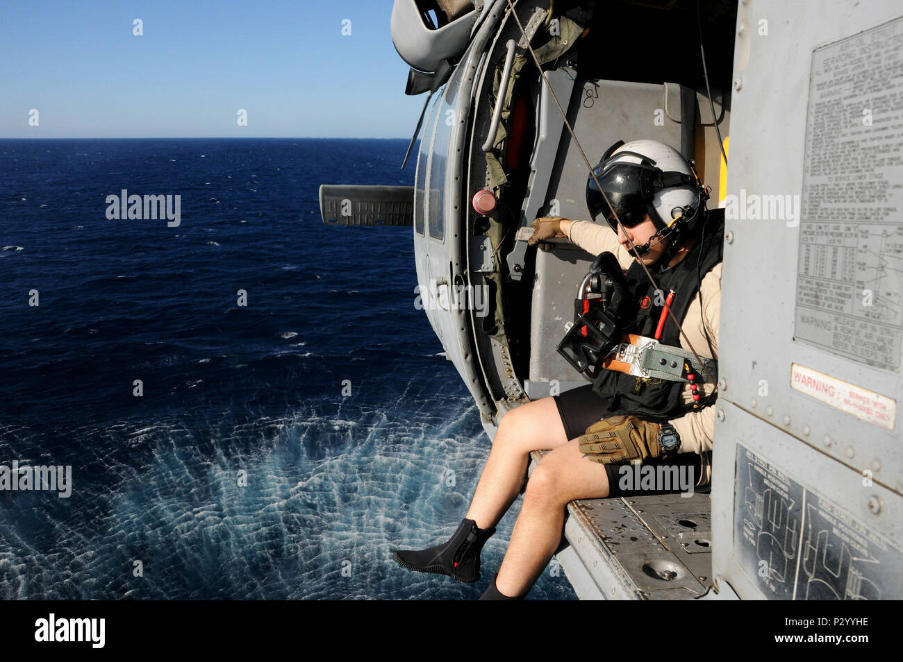 160812-N-XI307-638 ATLANTIC OCEAN (Aug. 12, 2016)  Naval Air Crewman (Helicopter) 3rd Class Dalton Gonzales sits on the edge of  an MH-60S helicopter attached to the 'Tridents' of Helicopter Sea Combat Squadron (HSC) 9 during search and rescue (SAR) training.The aircraft carrier USS George H.W. Bush (CVN 77) is underway conducting training and completing qualifications in preparation for a 2017 deployment. (U.S. Navy photo by Mass Communication Specialist 2nd Class Ryan Seelbach/Released) Stock Photo