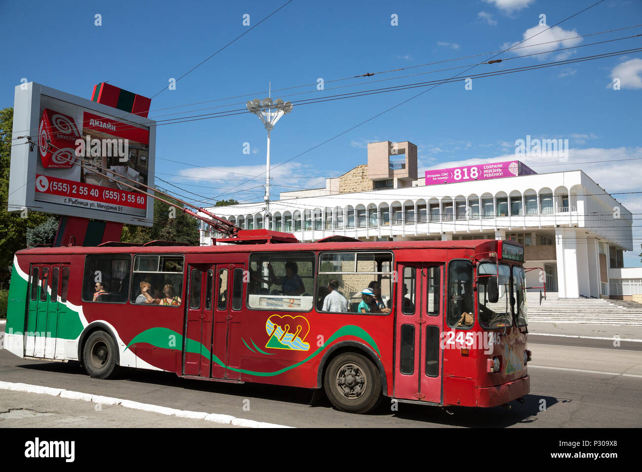 25.08.2016, Tiraspol, Transnistria, Moldova - Illuminated billboard and trolleybus in Transnistrian colors, behind the former Pioneer Palace (now: Pal Stock Photo