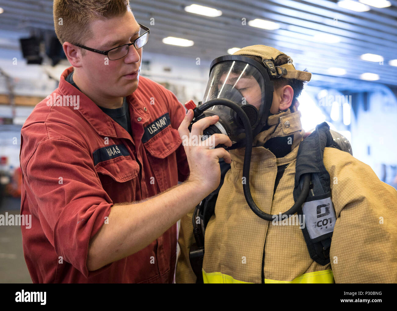 160811-N-WF272-024 EAST CHINA SEA (Aug. 11, 2016) Damage Controlman Fireman Cody Haas, from Appleton, Wis., helps Mass Communication Specialist 3rd Class Jeanette Mullinax, from Tampa, Fla., don firefighting equipment during Mobility – Damage Control (MOB-D) training aboard amphibious assault ship USS Bonhomme Richard (LHD 6). Bonhomme Richard, flagship of the Bonhomme Richard Expeditionary Strike Group, is operating in the U.S. 7th Fleet area of operations in support of security and stability in the Indo-Asia-Pacific region. (U.S. Navy photo by Mass Communication Specialist 2nd Class Diana Qu Stock Photo