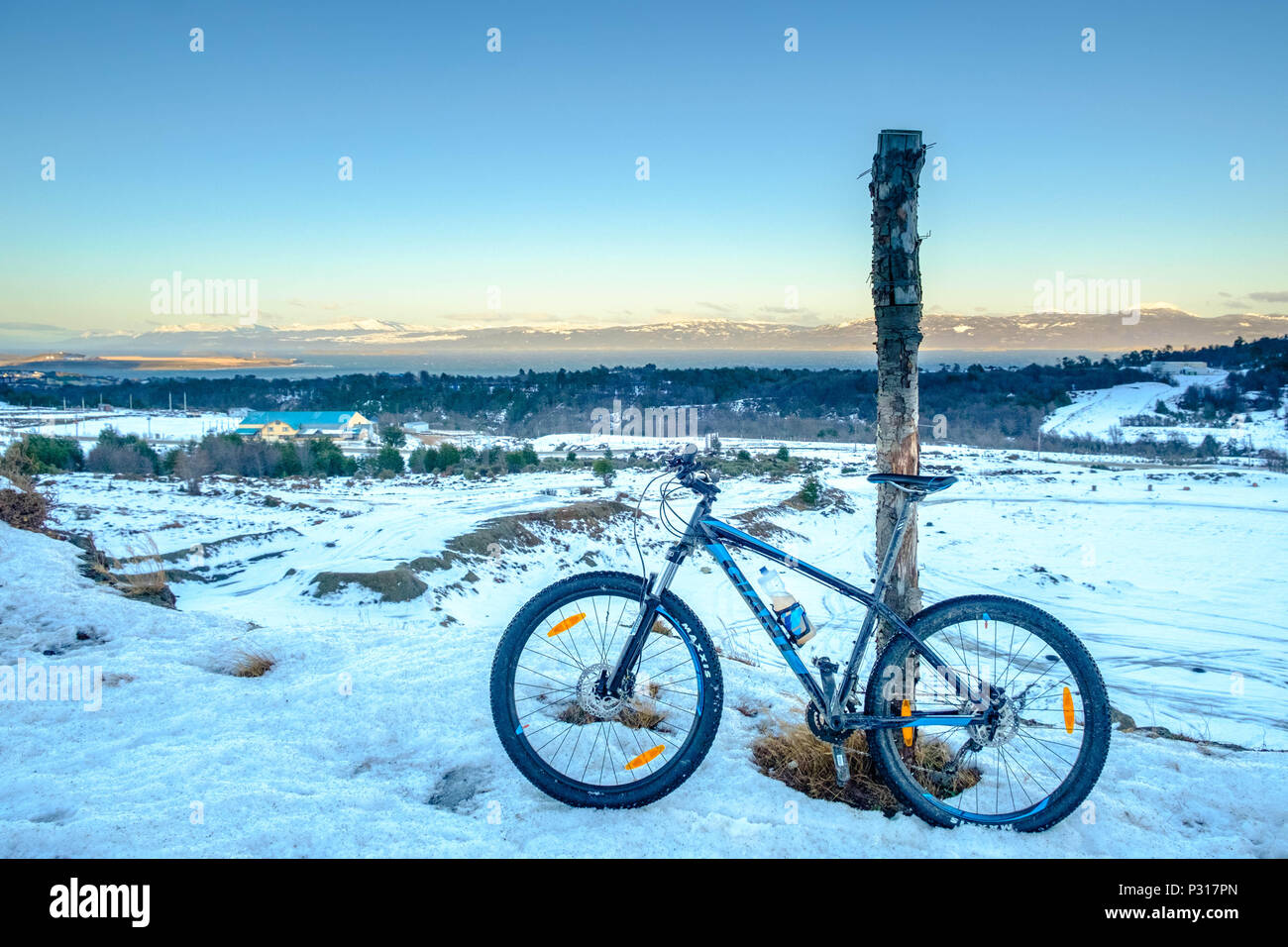 A Giant mountainbike stands against a pole in between Ushuaia and the National Park of Tierra del Fuego. Icy snow made the road very difficult. Stock Photo